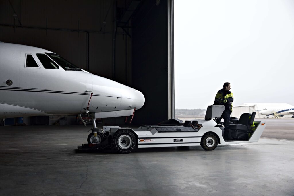 A man pulling a plane out of a hangar with a machine