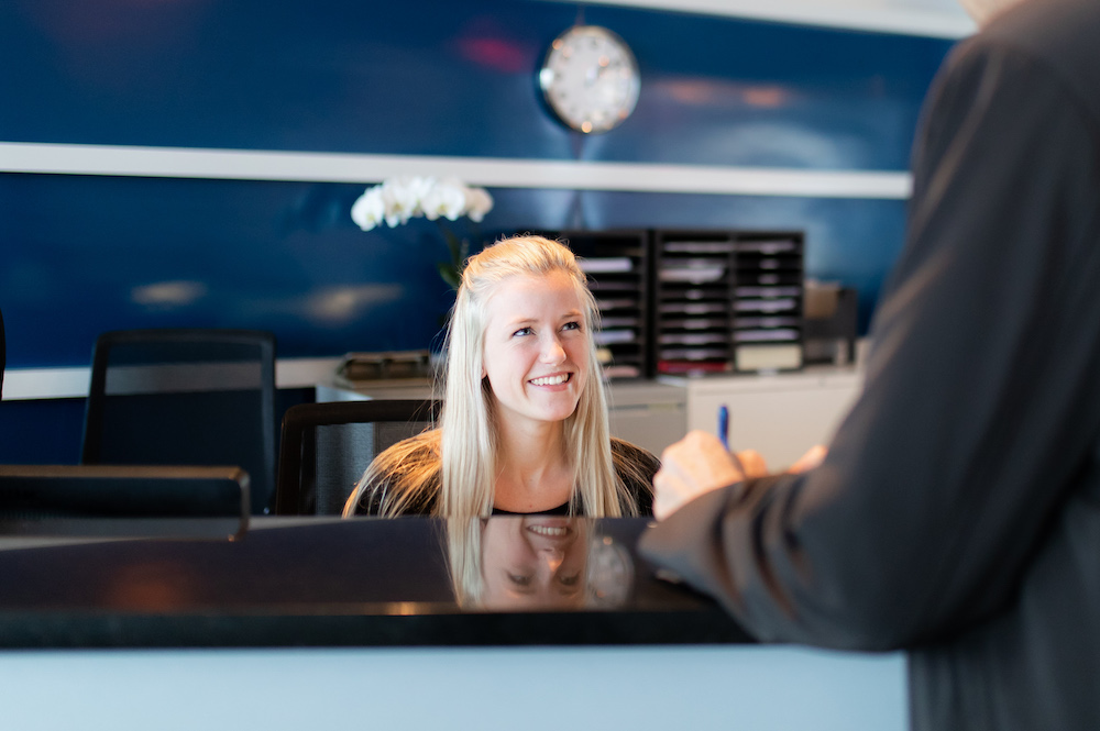 Female receptionist sitting and smiling while serving a customer