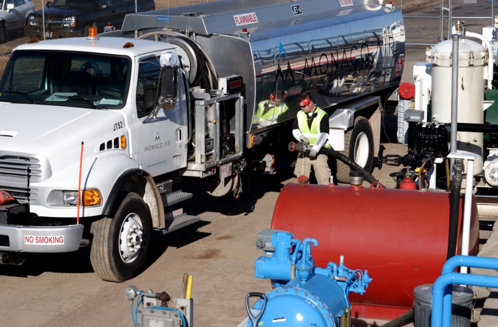 A man connecting a hose to a tanker truck
