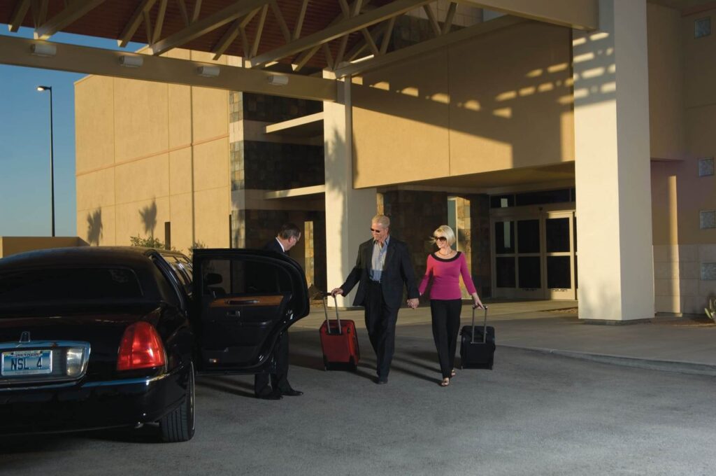 A man and a woman getting into a car with hand luggage