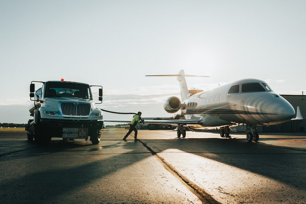 A fuel truck and an airplane stand on the tarmac