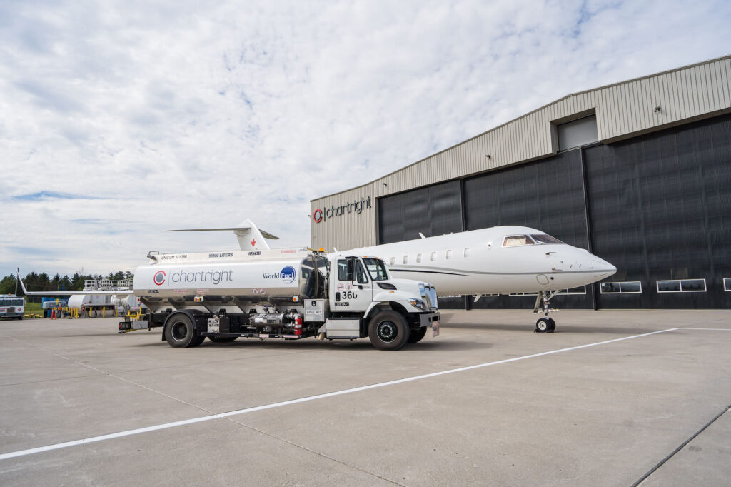 A car with the Chartright logo refuels the plane in front of the hangar